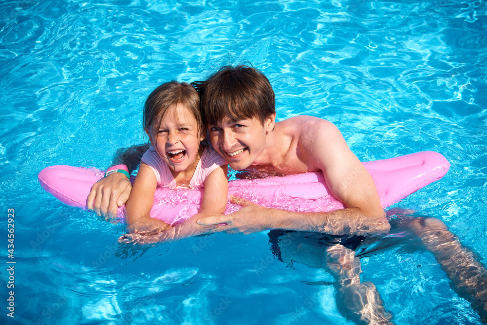 Dad and daughter are having fun in the pool. Family summer vacation in