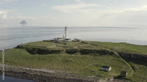 Aerial view of Pladda Lighthouse on the Isle of Arran on a sunny day, Scotland. Flying left to right around the lighthouse. Close view with zoom in. photo