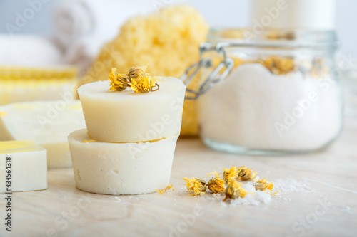 Solid shampoo bar many and handmade soap round bars with herbs dry marigold flowers. Spa bathroom products aroma salt, natural washcloth on marble table. Beauty cosmetics products for relax bodycare.