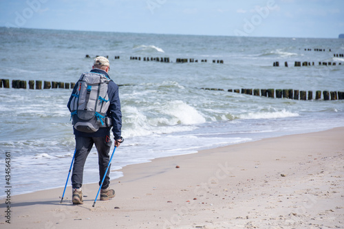 Fototapeta Naklejka Na Ścianę i Meble -  Traveler with Nordic walking poles walks along the coast of the Baltic Sea near the city of Kolobrzeg in Poland