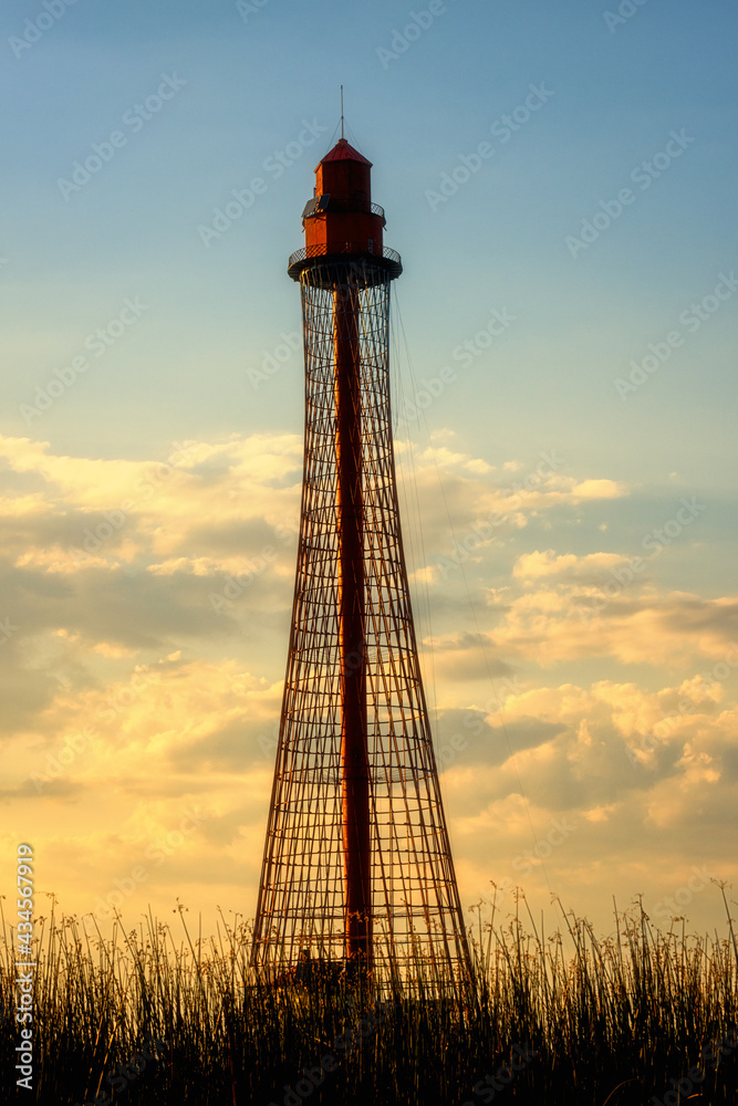 Adzhyholskyy mayak or Adziogol lighthouse also known as Stanislav range rear light in Dnieper estuary, Ukraine. Scenic sunset landscape with navigation construction, water, blue sky and reflection Adzhyholskyy mayak or Adziogol lighthouse also known as Stanislav range rear light in Dnieper estuary, Ukraine. Scenic sunset landscape with navigation construction, water, blue sky and reflection