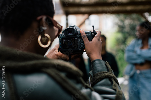 Close up of cool woman photographer with glasses and afro taking photographs with her camera 