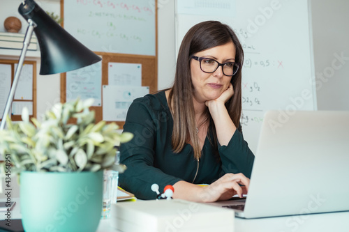 Female professor teaching students from home using a webcam video conference call on laptop computer. Experienced teacher holding online class for e-learning students during pandemic period. photo