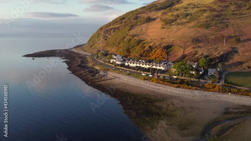 Aerial view of the Scottish town of Catacol on the Isle of Arran at sunset, Scotland. Right to left view flying away from the town with slow zoom in. photo