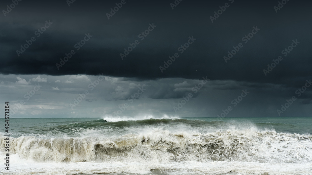 View of a stormy sea and dark cloudy sky, big waves are crashing on the shore