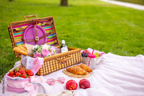 Picnic in the park under blooming cherry trees with fruit, wine, bread and croissants