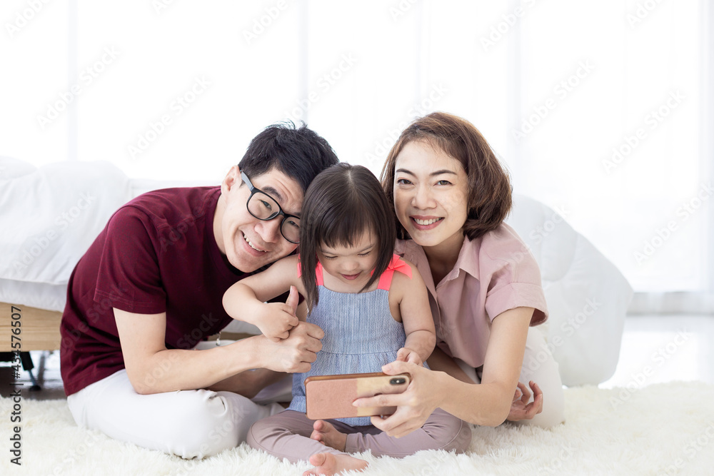 Girls with Down Syndrome cerebral learning disability, laughing, playing, parents in white bedrooms, teaching their children to watch educational materials using a smartphone. Happy education concept Girls with Down Syndrome cerebral learning disability, laughing, playing, parents in white bedrooms, teaching their children to watch educational materials using a smartphone. Happy education concept
