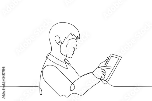 man pokes his finger into the screen of the tablet - one line drawing vector. profile portrait of a man using a touch gadget. viewing the news feed, internet surfin photo