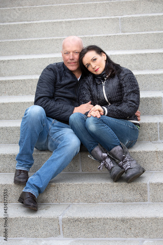 portrait of beautiful couple in their 50s sitting outside on steps