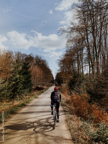 Cyclist riding along a road. Road cycling in forest.