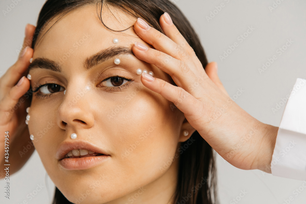 portrait of young woman hands near face with decorative makeup isolated on grey