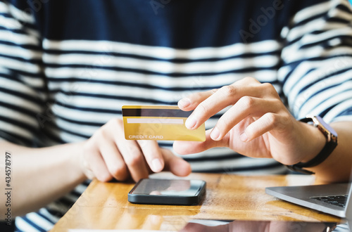 Pay online with man hand holding a credit card and using a smartphone for online shopping
