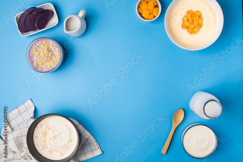 Flatlay of different flavors of yoghurt on blue background