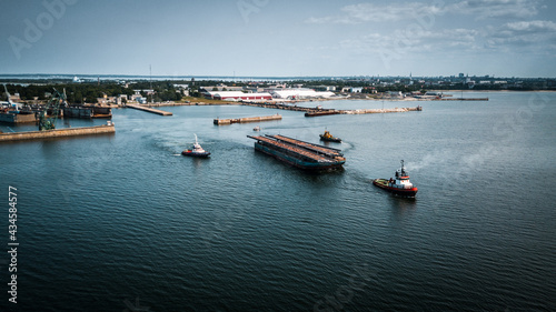 Aerial drone footage of industrial shipyard complex and ships towing cargo in the sea.   © roman
