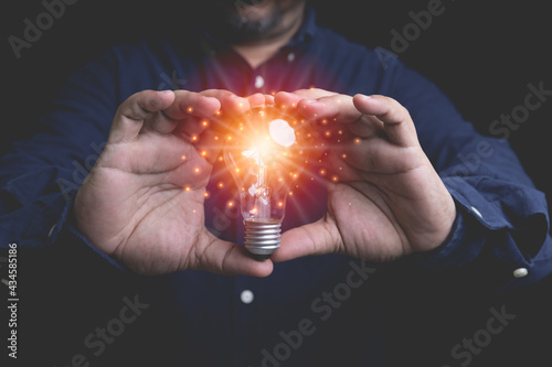 Businessman holding lightbulb symbol creative idea innovative with copy space and background. Innovation design forms an inspiration concept. Creativity with bulbs that shine glitter.