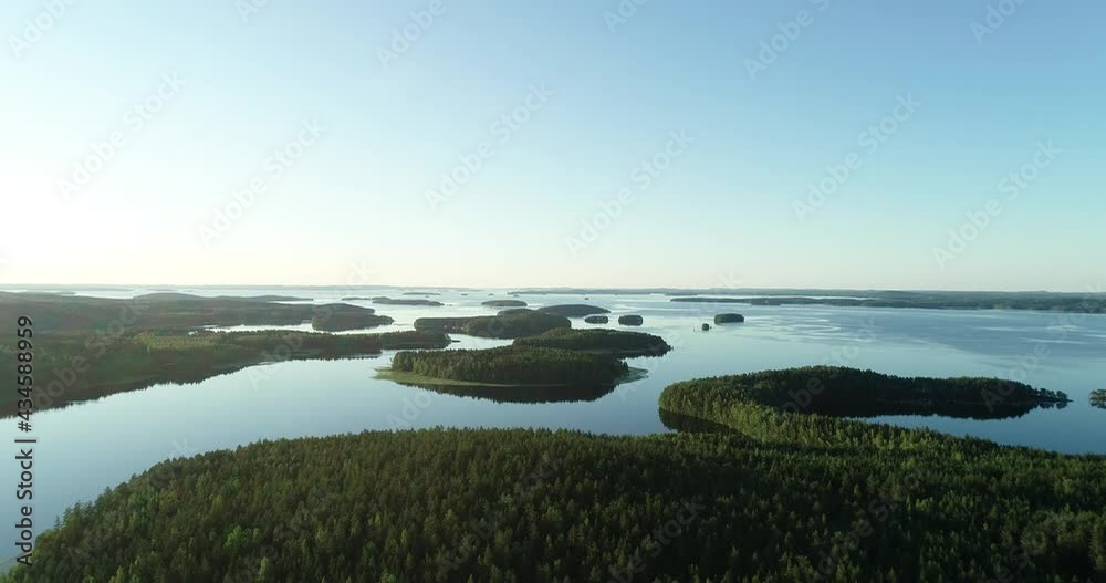 Aerial view of beautiful lake with islands and green forests in Finland on a sunny summer day. Drone footage
