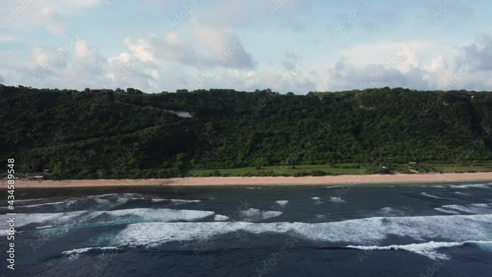 Nyang Nyang Beach along green cliff parallel move parallax with fluffy clouds in Bali Indonesia. High quality aerial 4k footage Nyang Nyang Beach along green cliff parallel move parallax with fluffy clouds in Bali Indonesia. High quality aerial 4k footage