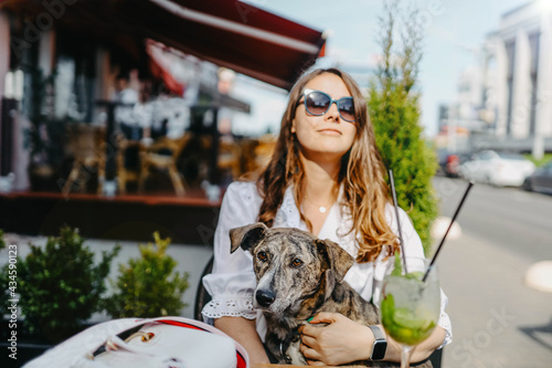 Dog with a young woman in a cafe restaurant on the terrace, dog friendly food establishments.