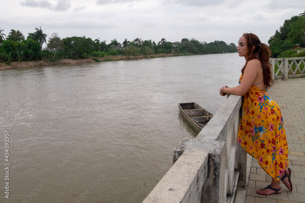 woman on boardwalk, looking towards the river