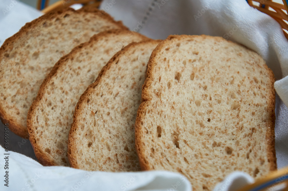 Cut grain bread in breadbasket with white towel close up
