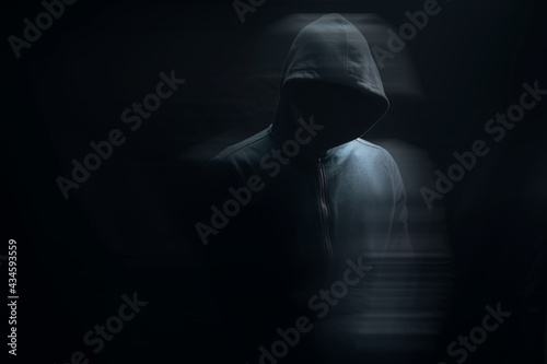 a man in a hood stands on a black background photo