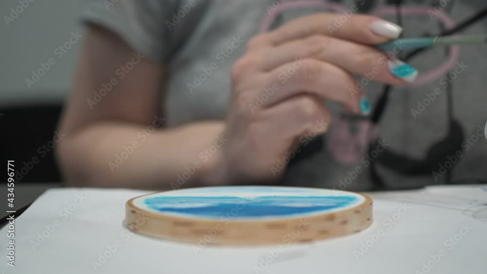 a woman mixes oil paints with a brush and paints on a tree. close-up a woman mixes oil paints with a brush and paints on a tree. close-up