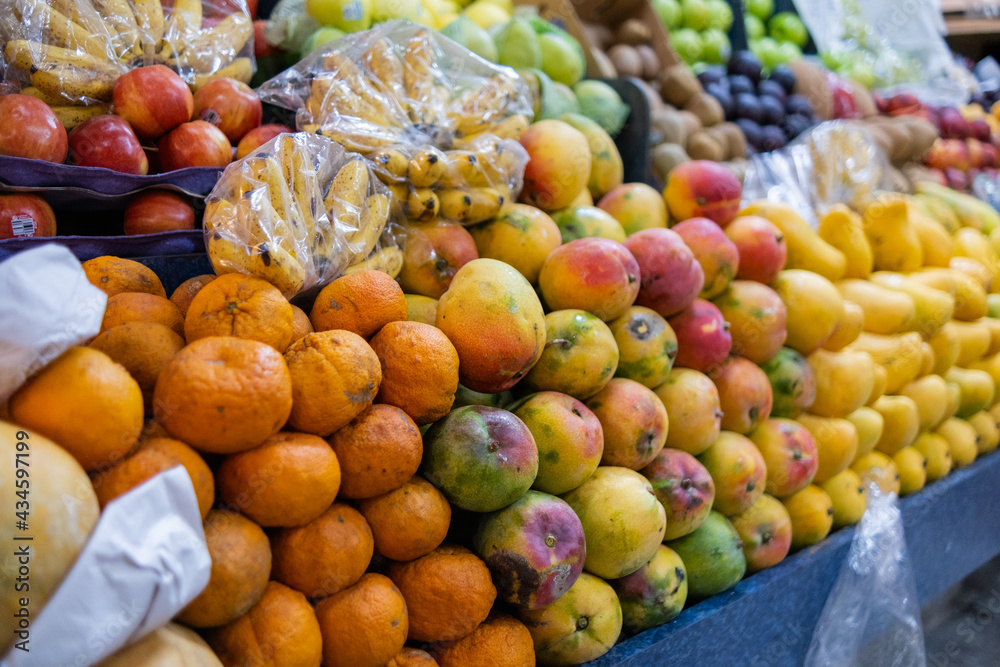 Colorful fruit stand with tangerines, apples, mangoes, bananas, and more