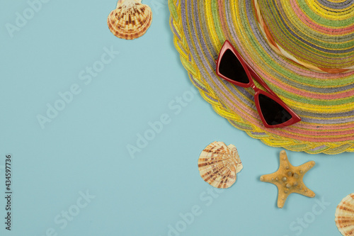 Summer background. Striped hat and red glasses on a light blue background. Top view, close-up, horizontal. Summer concept. Copy space.