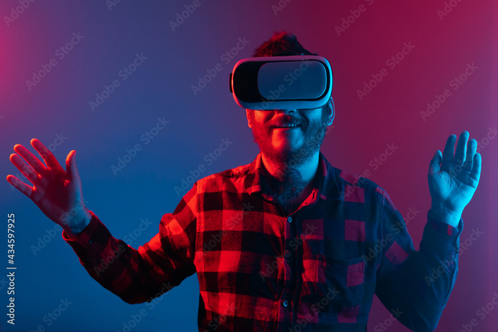 bearded man with tattoos having a virtual reality experience among neon lights. Person using VR glasses. leisure time and modern technology bearded man with tattoos having a virtual reality experience among neon lights. Person using VR glasses. leisure time and modern technology