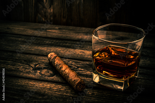 Glass of brandy and cuban cigar on an old wooden table. Angle view