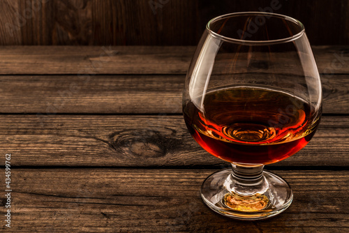 Glass of brandy and on an old wooden table. Angle view