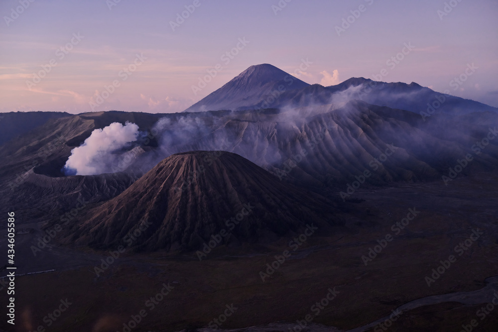 Mount Bromo volcano in East Java, Indonesia. Active volcano with crater in depth, surrounded with lake and covered in clouds of smoke. Mount Bromo volcano in East Java, Indonesia. Active volcano with crater in depth, surrounded with lake and covered in clouds of smoke.