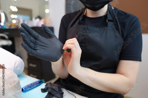 The tattoo artist puts on black sterile gloves on his hands to prepare for the procedure