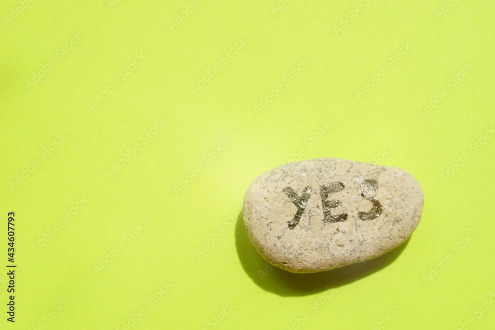 A pebble stone with the text yes on it. Green table A pebble stone with the text yes on it. Green table
