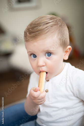 caucasian baby boy portrait with a biscuit in his mouth
