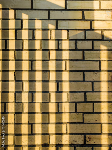 Horizontal, striped shadow on a yellow brick wall. Smooth, horizontal sunbeams. Unusual texture