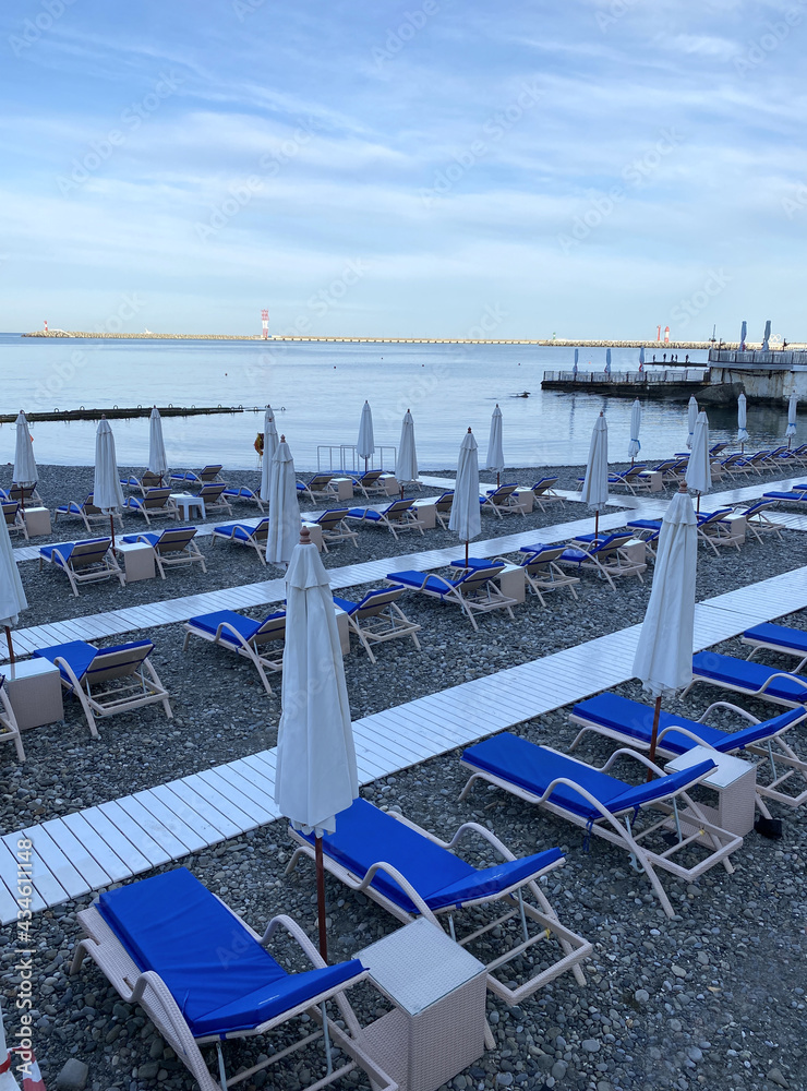 Sun beds and umbrellas on the first line of the sea. Hotel beach.