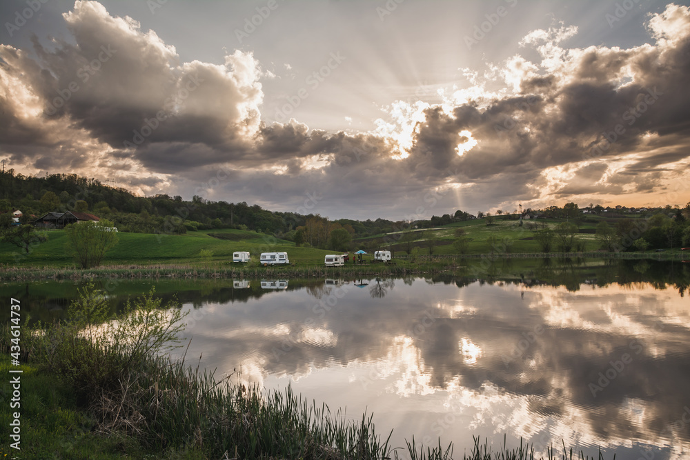 Sun is shining through the clouds above peaceful lake Sun is shining through the clouds above peaceful lake