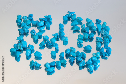 Turquoise jewel gemstones on grey mirror background, group of objects