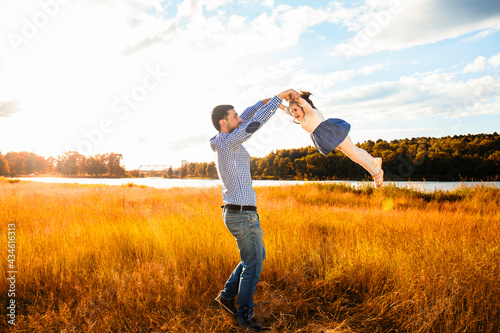 happy father with a little daughter, having fun in nature, in the rays of the sunset