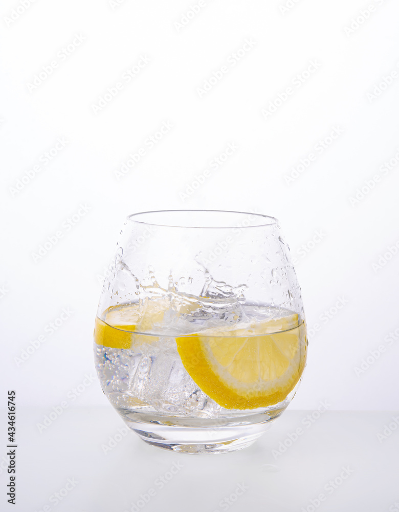 Glass with lemon mineral water and splashes on a white background. Front view and copy space Glass with lemon mineral water and splashes on a white background. Front view and copy space