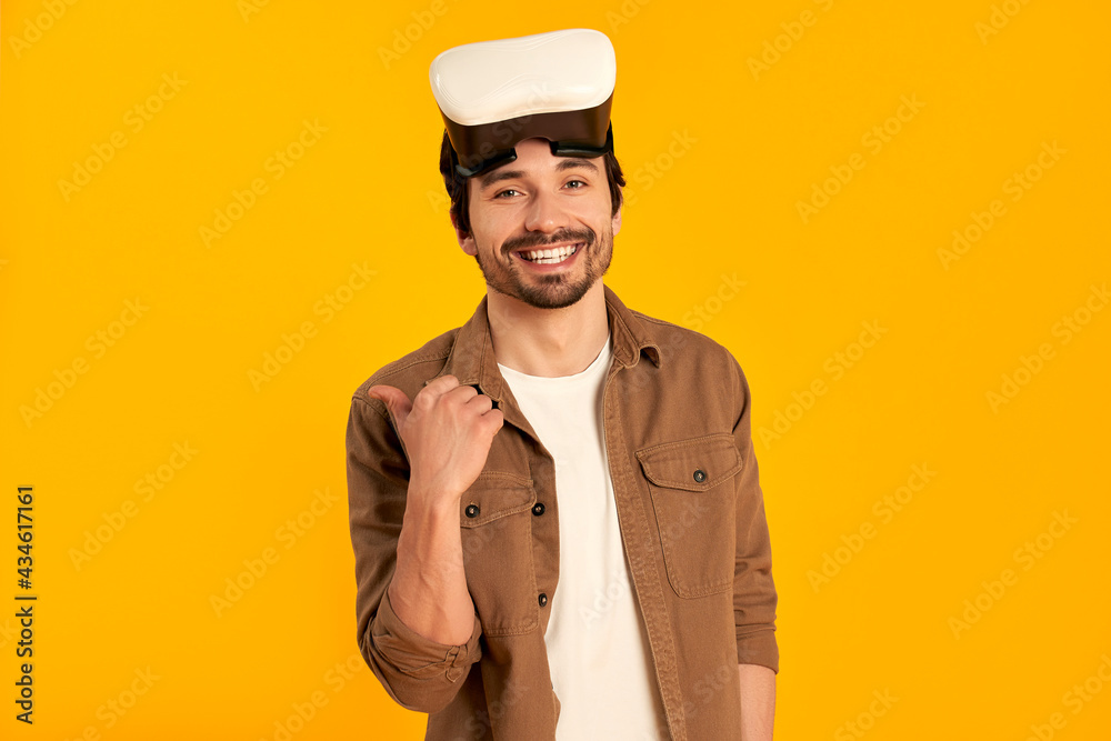 Young bearded man in virtual reality glasses isolated on orange background. Future technologies. Young bearded man in virtual reality glasses isolated on orange background. Future technologies.