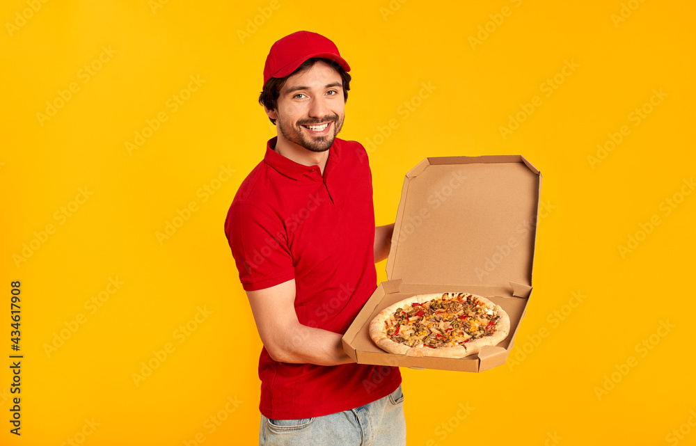 Young bearded pizza delivery man isolated on orange background. Home delivery. Young bearded pizza delivery man isolated on orange background. Home delivery.