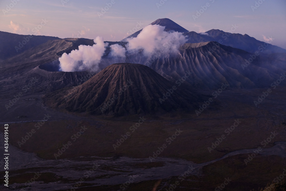 Landscape of active volcano with crater in depth, surrounded with lake and covered in clouds of smoke. Mount Bromo volcano (Gunung Bromo) in East Java, Indonesia.