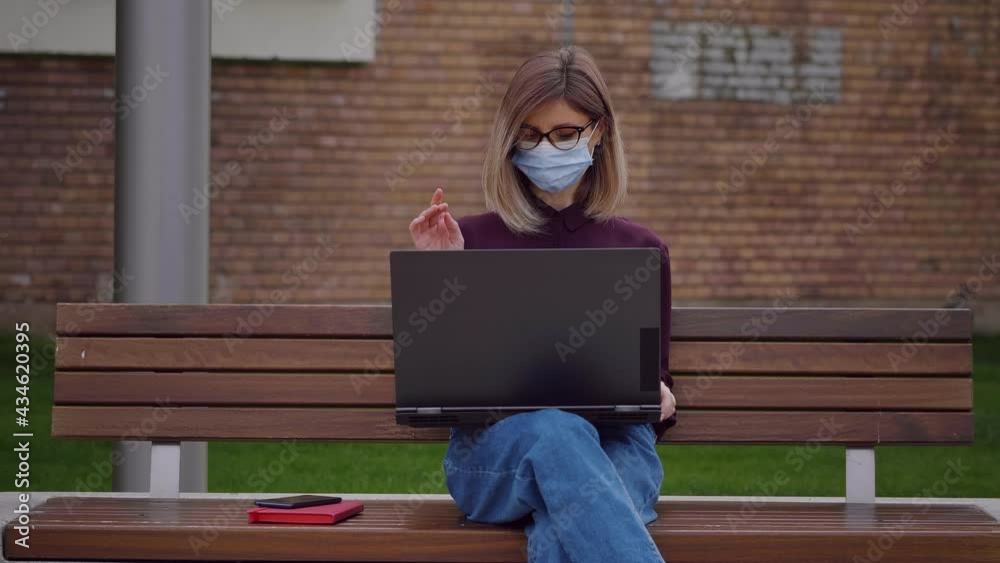 Business woman wearing medical mask working with laptop outdoors Satisfied young freelance blogger rejoices at finishing work. Business woman wearing medical mask working with laptop outdoors Satisfied young freelance blogger rejoices at finishing work.