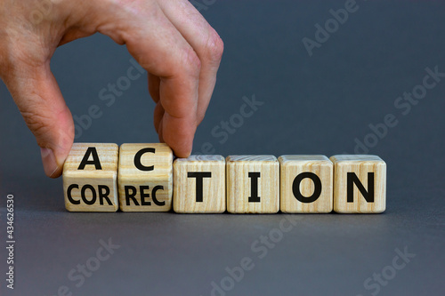 Action or correction symbol. Businessman turns wooden cubes and changes the word correction to action. Beautiful grey background, copy space. Business and action or correction concept. photo
