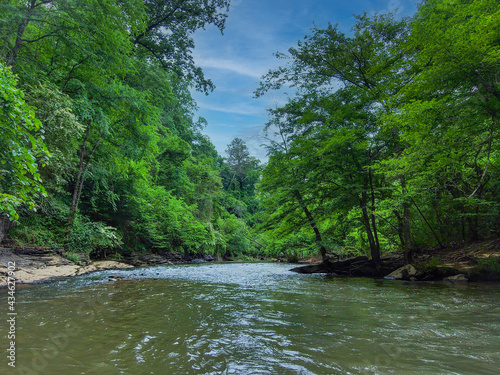 an aerial shot of the running waters of Big Creek River surrounded by miles of lush green trees and plant with rocks on the banks of the river and gorgeous sky at Vickery Creek in Roswell Georgia photo