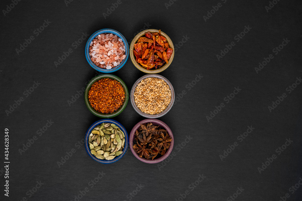 top view of small colorful containers filled with spices like cardamom, anise, himalayan salt, cayenne top view of small colorful containers filled with spices like cardamom, anise, himalayan salt, cayenne