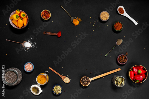 Top view of spoons and bowls filled with all kinds of spices and condiments