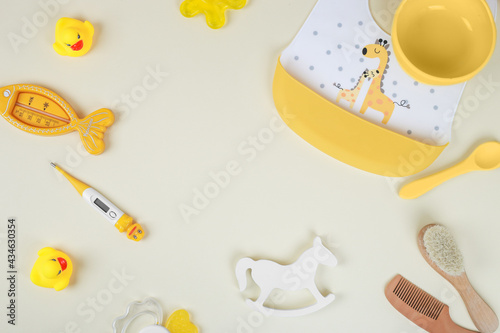 Baby accessories for bathing on yellow background, flat lay. Composition with baby accessories and space for text. Baby cotton swabs, cream, thermometer, ducks, combs, scissors, teething